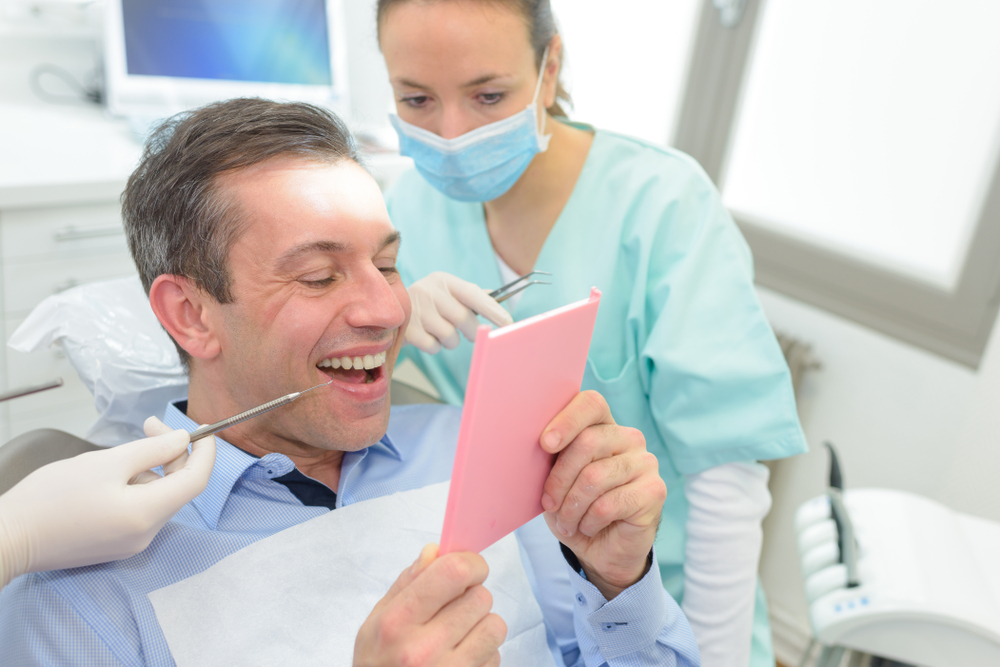 man smiling into mirror at dentist's