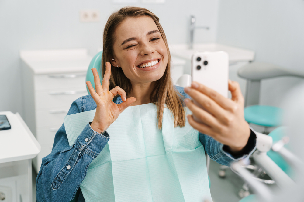 girl smiling taking selfie in dental chair